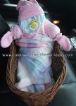 diaper baby in basket wrapped in pink blanket 