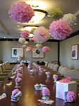 picture of an office baby shower in board room with vintage tea pots and tissue paper flowers and pom poms as decorations