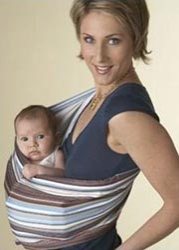 smiling mom wearing blue and brown striped baby sling with baby peeking out