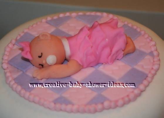 closeup of baby sleepeing on a pink a purple blanket cake