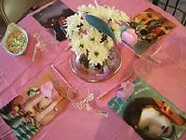 closeup of pink table at a baby shower with large alice and wonderland pictures as placeholders and white flowers in the center
