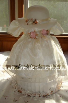 cream vintage baby dress and hat over a diaper cake