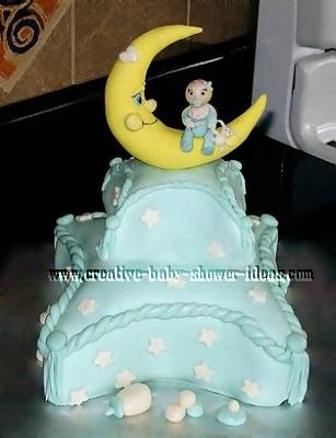 blue pillow cake with white stars and moon on top with baby sitting on it
