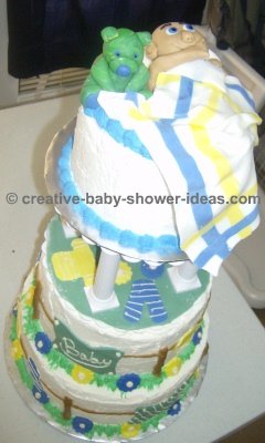 side of sleeping baby cake showing 3 tier cake on a cake stand and clothesline decoration on side