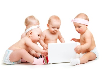 4 cute babies looking at computer that they are sitting around