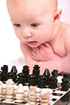 baby intently watching a game of chess