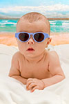 cute baby sitting on beach with glasses