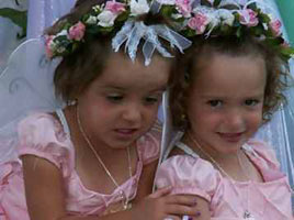 2 smiling girls with flower head wreaths and butterfly wings
