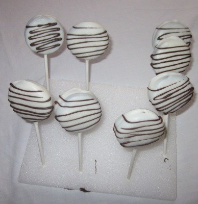white chocolate covered oreo lollipops standing up to dry