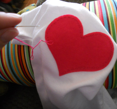sewing applique heart onto baby onesie