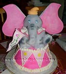 dumbo elephant baby shower cake holding banner and sitting on a drum 