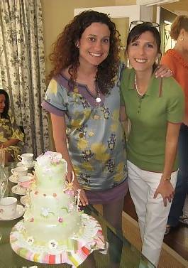 cake decorator next to mom to be and the baby shower cake