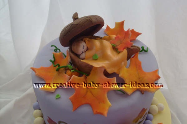 closeup of baby sleeping in acorn on top of cake using a leaf as a blanket