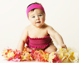 baby in pink tube top and headband surrounded by hawaiian flowers