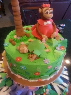 top of jungle cake with sister and baby monkeys on a green grass layer with palm trees