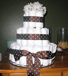 cowboy diaper cake with brown and teal polka dot ribbon and white flowers on top