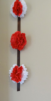 3 red and white paper flowers hanging vertical on brown ribbon
