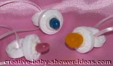 3 candy necklaces made to look like a baby pacifier tied to pink ribbon