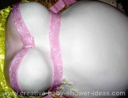 white baby shower belly cake with pink trim
