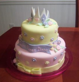 yellow and pink princess baby shower cake with purple and white crown on top