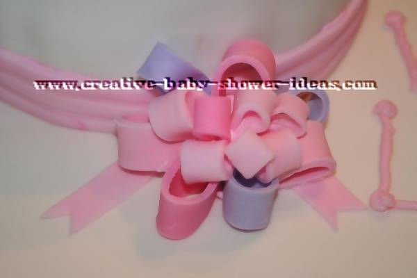 pink and purple flondant bow on baby cake