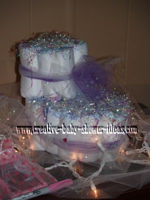 purple and white baby bootie diaper cake on table