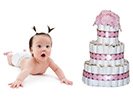cute surprised baby with pig tails next to pretty diaper cake