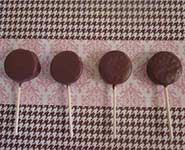 chocolate covered oreo lollipops on pink and brown background