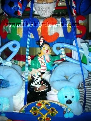 closeup of 1st layer of the circus diaper cake with a plastic clown and plastic safety pins