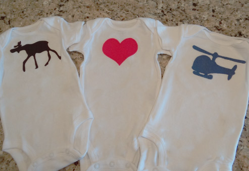 applique heart, helicopter and moose onesies on counter