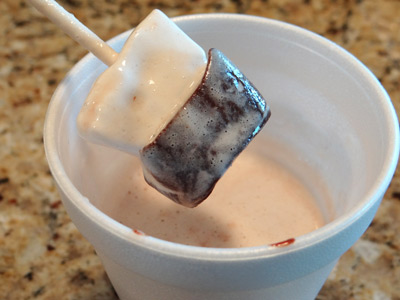 hot chocolate on a stick being stirred into warm milk