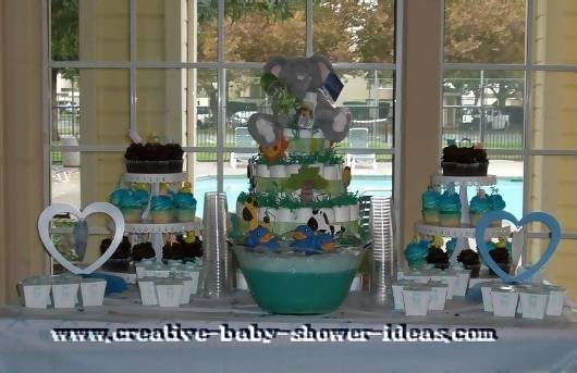 jungle diaper cake on baby shower table with 2 cupcake stands green punch heart decorations and favor boxes