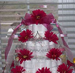 5 tier white princess diaper cake with pink daisies and sheer white ribbon