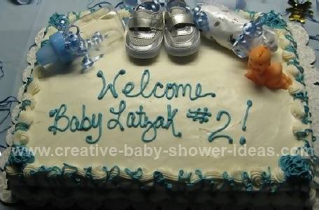 white baby cake with silver baby shoes and blue writing 