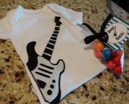 white baby onesie with black and white appliqued guitar