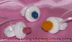 3 candy necklaces made to look like a baby pacifier tied to pink ribbon