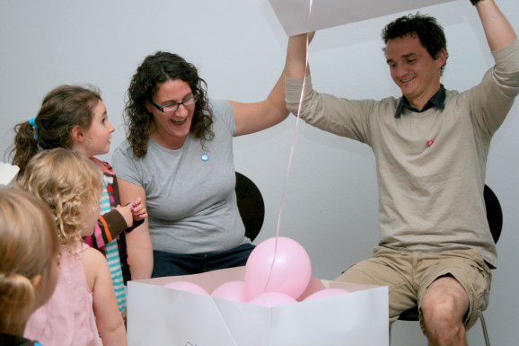 happy mom and dad at gender reveal opening box and seeing pink balloons