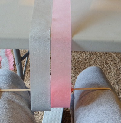 wooden dowel threaded on crepe paper rolls sitting on legs