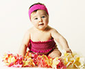 baby in pink sun dress and headband, surrrounded by hawaiian flowers