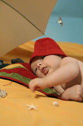baby lying on the beach with umbrella
