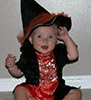 cute baby girl in black and orange witches outfit and hat