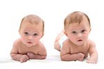 2 twin boys lying on their stomachs looking at camera