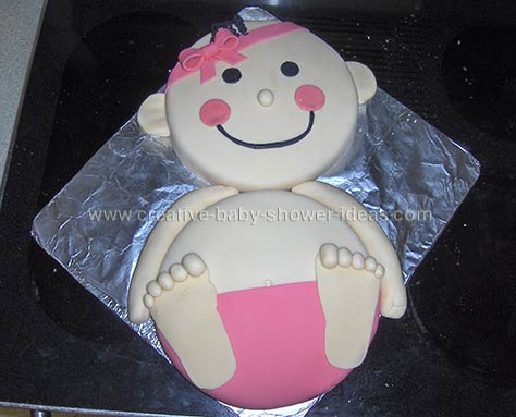 smiling baby girl cake with pink fondant diaper and headband