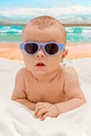 cute baby sitting on beach with glasses