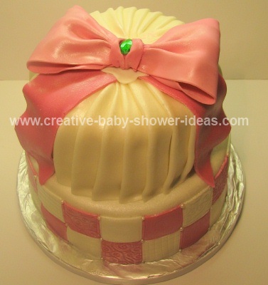 top of pink and white baby shower crown cake showing pink bow and emerald stone