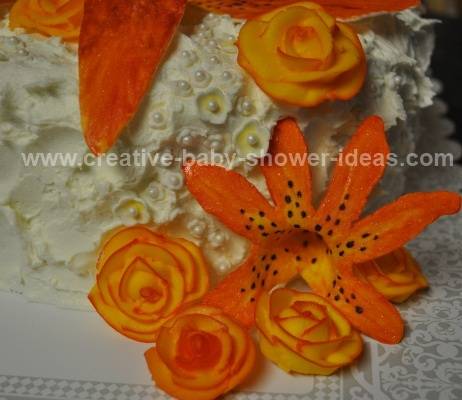 sideview of baby cake showing different orange flowers and edible white pearls