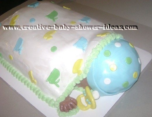 sleeping baby lying on its belly with white blanket and blue cap decorated with polka dots and bunnies